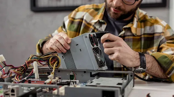 Networks technician repairing a desktop PC power supply for a Long Island business — managed IT services vs break-fix support.